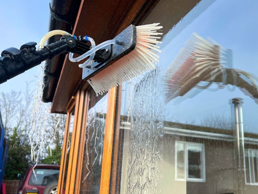 Water-fed brush cleaning a home's exterior window